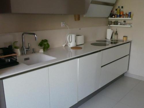une cuisine avec des armoires blanches et un évier dans l'établissement Le Rocher Des Sanguinaires, à Ajaccio