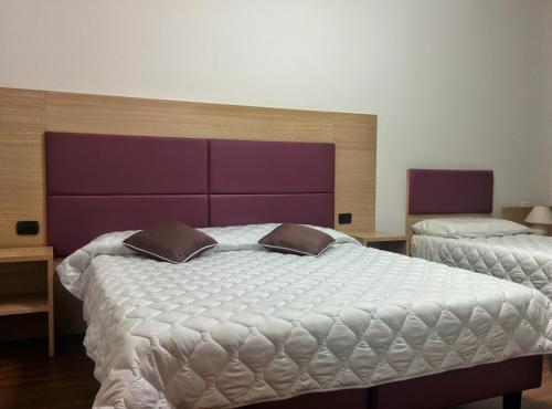 a bedroom with two beds with purple and white sheets at Hotel Esperanza in Florence