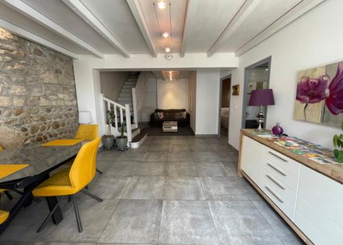 a dining room with yellow chairs and a stone wall at Petite'Escale in Charmes-sur-Rhône