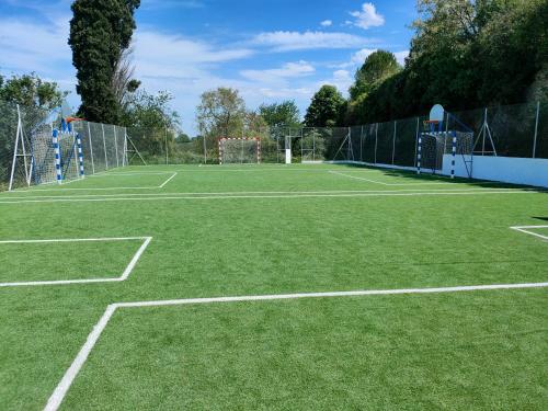 a tennis court with green grass and a net at Le Pitstop in Alan