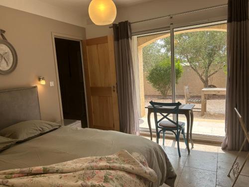 1 dormitorio con cama, mesa y ventana en Au ciel étoilé, en Castillon-du-Gard