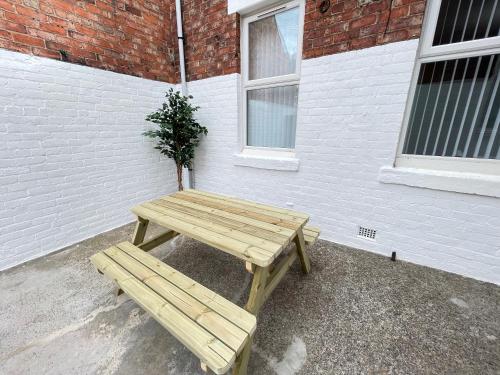 a wooden picnic table in front of a brick building at Belford Apartment, Close to Tynemouth in Tynemouth