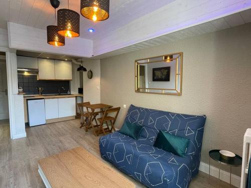 un salon avec un canapé bleu et une cuisine dans l'établissement F2 Résidence Eurotel n°5 avec vue sur le Cher, Centre - Ville, à Montluçon