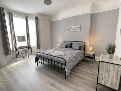 a bedroom with a bed and a desk and windows at Belford Apartment, Close to Tynemouth in Tynemouth