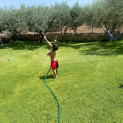 a boy in a yard with a water hose at Nasia’s house in Kineta