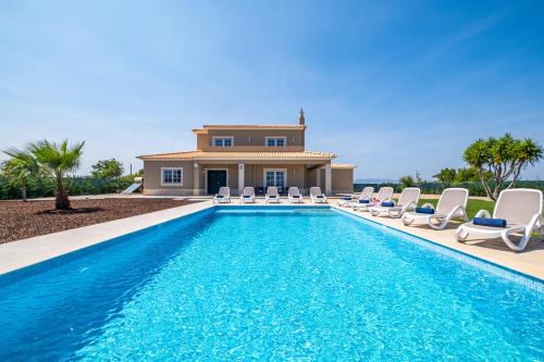 Villa mit einem Pool mit Stühlen und einem Haus in der Unterkunft Villa Paradise by Algarve Vacation in Lagoa