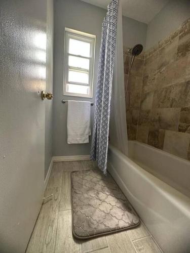 a bathroom with a shower and a tub and a window at Minutes away from Clearwater beach in Clearwater