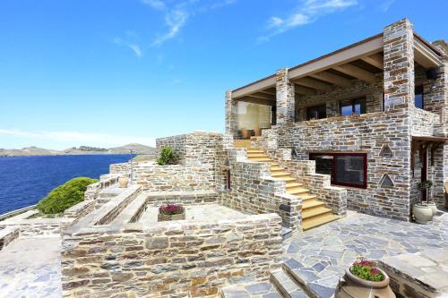 a stone house on the water with stairs at KEOS by the sea in Korissia