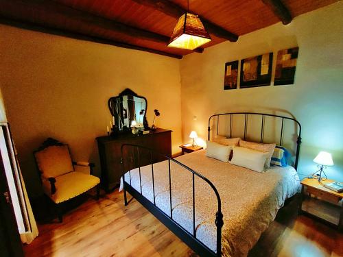 1 dormitorio con cama, silla y espejo en Casa Rural El Cencerro, en Villamanrique de Tajo