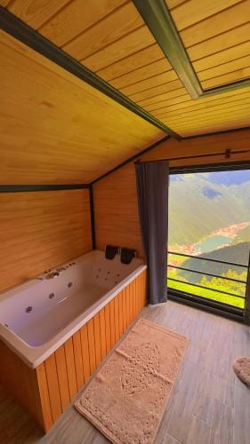 a large bath tub in a room with a large window at Panorama Uzungöl in Uzungöl
