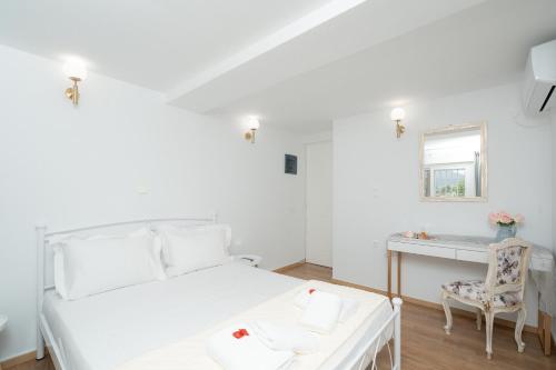 - une chambre blanche avec un bureau et un lit dans l'établissement Livingstone Cottage by A&D Properties, à Pórto Ráfti