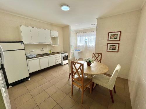 a small kitchen with a table and a refrigerator at Apartamentos Grandes - 3 quartos com suíte in Piracicaba