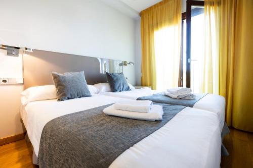 two beds in a hotel room with towels on them at Villa Elisa by Basquelidays in Hondarribia