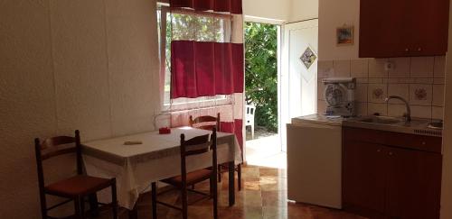 une cuisine avec une table et des chaises ainsi qu'une fenêtre dans l'établissement M&M 7, à Crikvenica