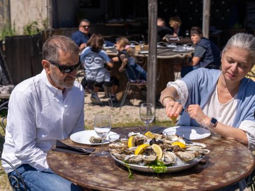 un homme et une femme assis à une table avec une assiette de nourriture dans l'établissement Joli studio vue Mont Saint Clair, parking, ménage et linge de lit inclus, à Sète