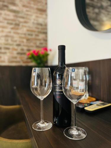 a bottle of wine and two wine glasses on a table at Arena Prestige Rooms in Pula