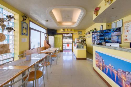jadalnia ze stołami i krzesłami oraz żółtymi ścianami w obiekcie Hotel Nuova Aurora w mieście Marghera
