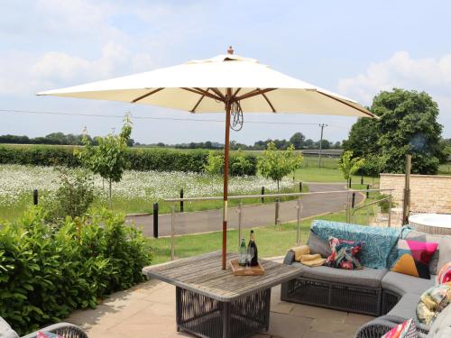 a patio with a table with an umbrella at The Anchorage Nables Farm in Chippenham