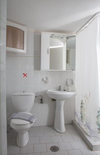 a white bathroom with a toilet and a sink at Mary's Studios in Agia Pelagia