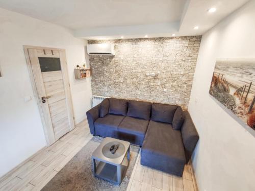 a living room with a couch and a brick wall at Konik Morski in Jastarnia