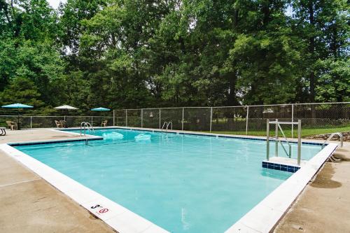 a large swimming pool with blue water in front of a fence at Tranquil Luxury: Modern Comfort! in Lynchburg