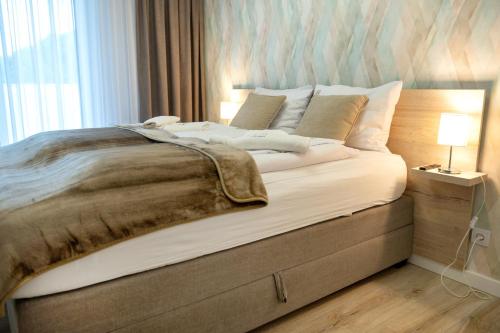 uma cama grande num quarto com um candeeiro no chão em Platinium Moon - przy samym morzu - Easy-Rent Apartments em Rewal
