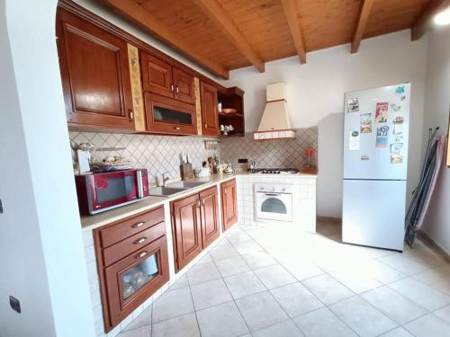 uma cozinha com armários de madeira e um frigorífico branco em Un passo dal mare e dalla città. em Cagliari