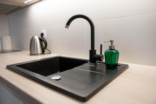 um lavatório de cozinha preto com uma garrafa verde em Platinium Moon - przy samym morzu - Easy-Rent Apartments em Rewal