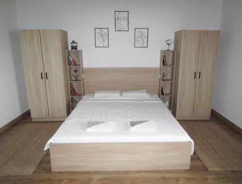 ein Schlafzimmer mit einem großen Bett und Holzschränken in der Unterkunft OBALA apartman in Subotica