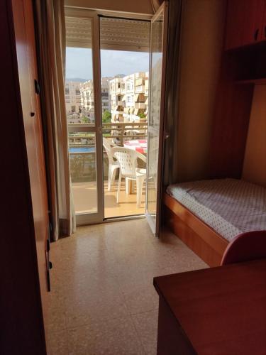 Habitación con cama y balcón con mesa. en Piso Loli en Málaga