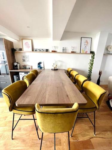 - une grande table en bois avec des chaises jaunes dans l'établissement House near Paris/Stade de France, à Saint-Denis