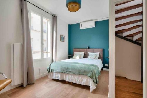 um quarto com uma cama e uma parede azul em House near Paris/Stade de France em Saint-Denis