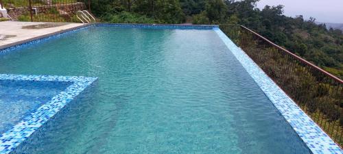 a large swimming pool with blue water and trees at HillTop in greany meadows yercaud in Yercaud