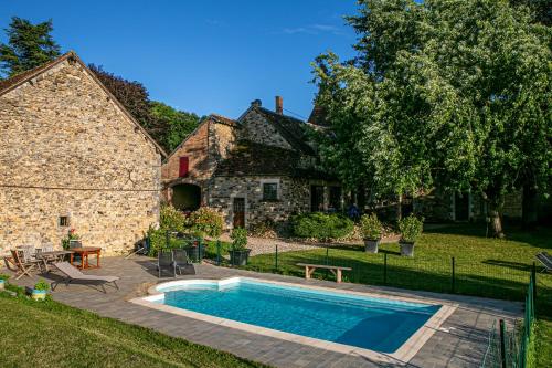 a swimming pool in front of a stone house at Maison Forte Perreuse in Treigny