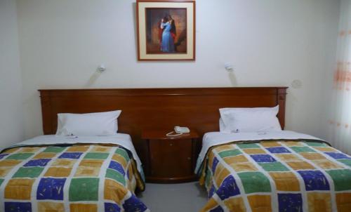 sypialnia z 2 łóżkami i zdjęciem na ścianie w obiekcie RIZZO HOTEL w mieście Chiclayo