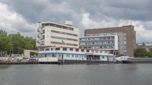 マーストリヒトにあるNautica Jansenの船が建物の前に停泊している
