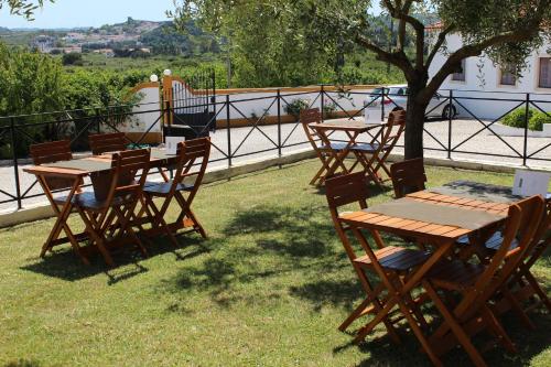 a group of wooden tables and chairs under a tree at Casa de Campo Sao Rafael - Turismo Rural in Óbidos