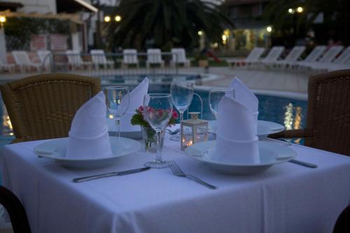 a table with plates and wine glasses on a table with a pool at Konstantina Apartments in Kavos