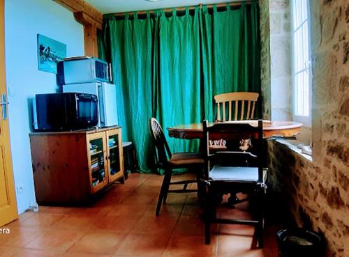a living room with a table and chairs and a television at Chambres d'Hôtes Le Foursou in Le Bouyssou