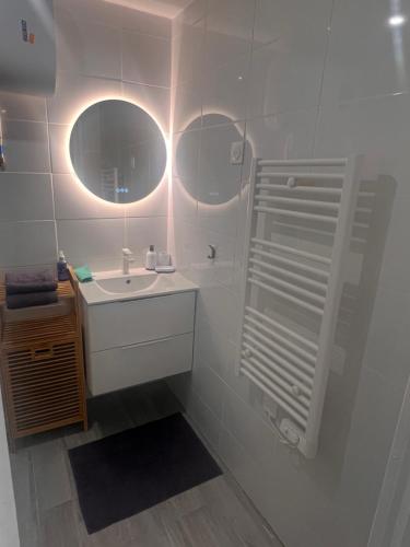 La salle de bains blanche est pourvue d'un lavabo et d'un miroir. dans l'établissement Studio 2prs Tout Equipé Et Neuf, à Marseille