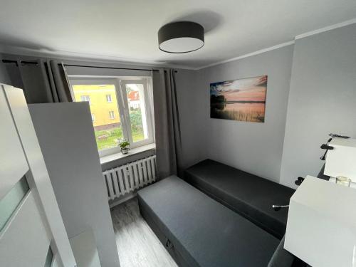 ein kleines Zimmer mit einem Sofa und einem Fenster in der Unterkunft Apartament Reszel in Reszel