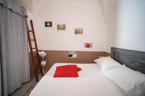 een slaapkamer met een bed met een rood kussen erop bij Casa Le Mura in Ostuni