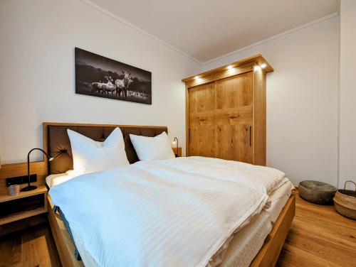 a bedroom with a large white bed with a wooden headboard at Das Wipferl - Dein Nest in den Bergen in Maria Luggau
