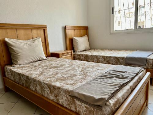1 dormitorio con 2 camas y ventana en Cozy Apartment in Salam center, en Agadir