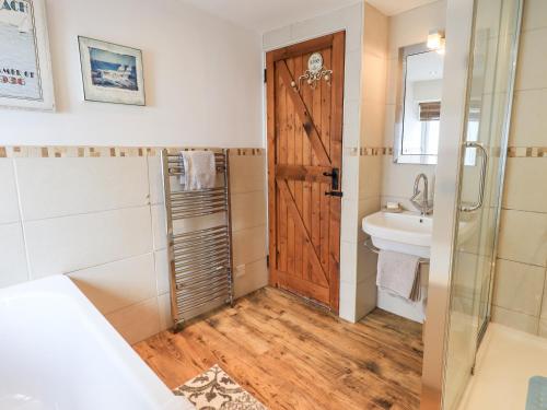 a bathroom with a wooden door and a sink at 4 Greencross Cottages in Holme