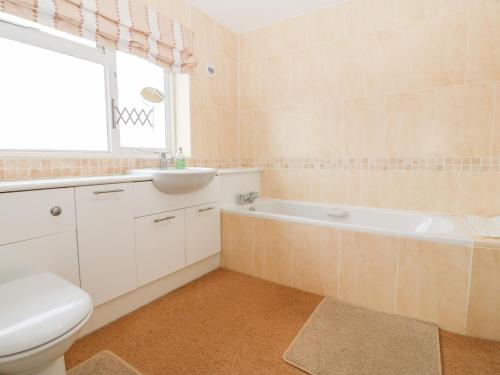 a bathroom with a toilet and a sink and a tub at 11 Min Y Mor in Pwllheli