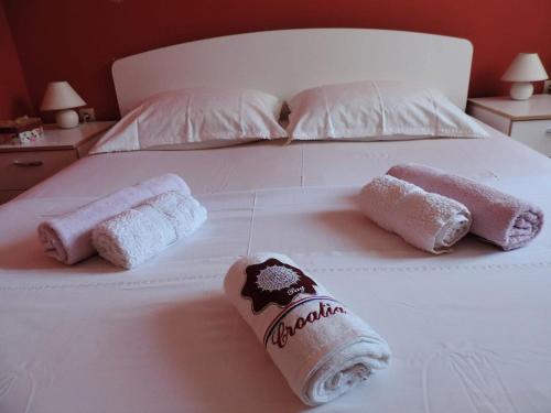a white bed with two rolled towels on it at Rooms & studio OLD TOWN PAG in Pag