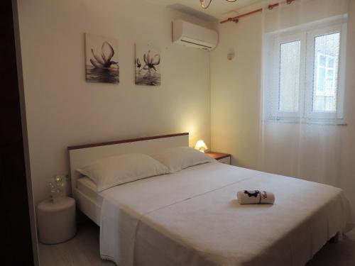 a bedroom with a bed with a white bedspread and two pictures at Rooms & studio OLD TOWN PAG in Pag