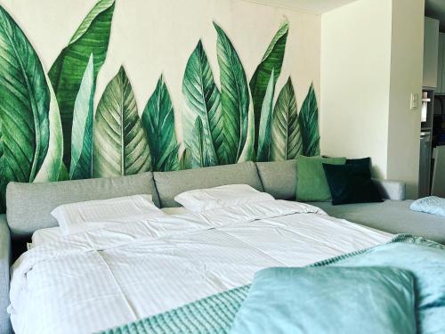 - une chambre avec un grand lit orné d'une fresque murale représentant des feuilles dans l'établissement Sfeervolle vakantiewoning aan zee, à Ostende