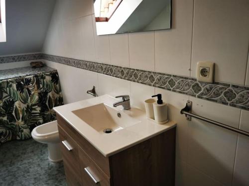 uma casa de banho com um lavatório, um WC e um espelho. em Ático Río Pego em Ángeles